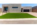 Contemporary home showcasing an artificial lawn, desert landscaping, and a brick driveway at 5744 E Lowden Rd, Cave Creek, AZ 85331
