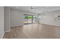 Bright, empty living room featuring wood floors, a fan, recessed lights, and a sliding glass door at 15634 W Georgia Dr, Surprise, AZ 85379