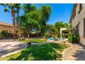 Spacious backyard featuring manicured lawn, lush landscaping, a pool, and stone detailing at 18402 E Oak Hill Ln, Queen Creek, AZ 85142