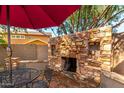 Outdoor living space featuring a stone fireplace and comfortable seating area under a red umbrella at 18402 E Oak Hill Ln, Queen Creek, AZ 85142