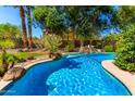 Lush backyard oasis with a sparkling pool, waterfall feature, and mature trees for privacy at 18402 E Oak Hill Ln, Queen Creek, AZ 85142