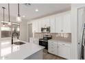 Modern kitchen features white cabinets, stainless steel appliances, stylish backsplash, and an island sink with pendant lighting at 18778 E Panchito Dr, Gold Canyon, AZ 85118