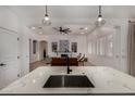 Open-concept kitchen with marble countertops, a stainless steel sink, and views of the living room with a fireplace at 465 E Frances Ln, Gilbert, AZ 85295