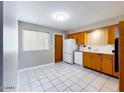 Open kitchen featuring wood cabinets, white appliances, and white tiled floor with natural light at 5414 E Albany St, Mesa, AZ 85205