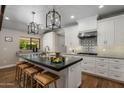 Bright kitchen with black island, pendant lighting, white cabinetry, and stainless steel appliances at 8343 E Quarterhorse Trl, Scottsdale, AZ 85258