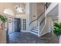 Grand foyer with soaring ceilings, iron staircase, wood-look floors, and decorative chandelier at 12042 S 44Th St, Phoenix, AZ 85044