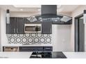 Modern kitchen featuring dark cabinets, stainless steel appliances, stylish backsplash, and sleek countertops at 12431 N 30Th Ave, Phoenix, AZ 85029