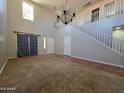 Spacious living room featuring high ceilings, a chandelier, and staircase at 25748 W Siesta Way, Buckeye, AZ 85326