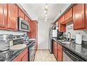 Galley kitchen featuring dark countertops, stainless steel appliances, and warm wood cabinets at 2625 E Indian School Rd # 206, Phoenix, AZ 85016