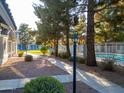 Sidewalk near a community pool featuring mature trees, landscaping and iron fence at 860 N Mcqueen Rd # 1151, Chandler, AZ 85225