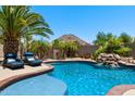 Tranquil pool featuring a rock waterfall and comfortable lounge chairs, creating a serene backyard oasis at 1078 W Desert Aster Rd, San Tan Valley, AZ 85143