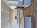 Modern kitchen boasting white cabinets, tile backsplash, island with black faucet and wood look floors at 17304 W Royal Palm Rd, Waddell, AZ 85355