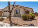 Attractive front yard with desert landscaping framing a charming beige home, complete with a well-kept lawn and inviting entrance at 17649 W Buchanan St, Goodyear, AZ 85338