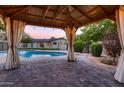 Relaxing backyard gazebo overlooking a sparkling in-ground pool and landscaped yard at dusk at 2518 E Flower E St, Phoenix, AZ 85016
