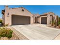 Spacious driveway leading to a three-car garage with desert landscaping at 26161 W Siesta Ln, Buckeye, AZ 85396