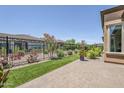 Cozy backyard with well-maintained artificial grass, brick pavers, and desert landscaping behind a black fence at 699 E Watermelon Ln, Queen Creek, AZ 85140