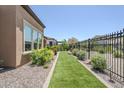 A tidy side yard with artificial turf and desert landscaping enclosed by a wrought iron fence at 699 E Watermelon Ln, Queen Creek, AZ 85140