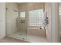 Luxurious shower featuring neutral tile, glass enclosure, built-in bench, and unique glass block window at 7152 E Night Glow Cir, Scottsdale, AZ 85266