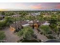 A beautiful home featuring mature palm trees, desert landscaping, and a circular driveway at 7640 E Poinsettia Dr, Scottsdale, AZ 85260