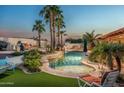 Backyard pool with palm trees, a waterfall feature, lounge chairs, and lush tropical landscaping at 10523 E Sleepy Hollow Trl, Gold Canyon, AZ 85118