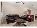 Inviting living room showcasing comfortable leather seating, tile flooring, and natural light from a window at 11206 W Coronado Rd, Avondale, AZ 85392