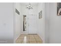 Bright foyer featuring neutral tile flooring, a modern light fixture, and a window for natural light at 11550 W Mule Deer Ct, Surprise, AZ 85378