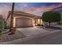 Dusk view of a home featuring a well-manicured front yard and a two-car garage at 11550 W Mule Deer Ct, Surprise, AZ 85378