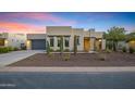 Contemporary home with desert landscaping, a gray garage door, and an inviting entryway is showcased at twilight at 11717 W Red Hawk Dr, Peoria, AZ 85383