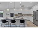 Bright kitchen boasts a large island, stainless steel appliances, ample white cabinetry, and modern pendant lighting at 11717 W Red Hawk Dr, Peoria, AZ 85383