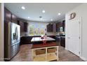 Spacious kitchen with dark cabinetry, stainless steel appliances, and a center island with a breakfast bar at 20545 W Terrace Ln, Buckeye, AZ 85396