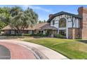 Beautiful brick home with a manicured lawn, mature trees and unique Tudor detailing on the facade at 211 W Kaler Dr, Phoenix, AZ 85021