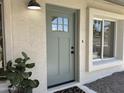 Close up of sage front door with glass accents, framed by white trim and a sleek, modern light fixture at 2753 E Aster Dr, Phoenix, AZ 85032