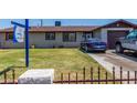 Modest single-story home with a brown roof, a blue car parked on the driveway, and a small fenced front yard at 6063 W Earll Dr, Phoenix, AZ 85033