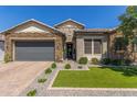 Charming single-story home featuring a stone facade, tile roof, desert landscaping, and a gray two-car garage at 9029 S 15Th St, Phoenix, AZ 85042
