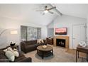 Bright living room with a fireplace, ceiling fan, comfortable seating, and natural light from a large window at 10115 E Mountain View Rd # 2061, Scottsdale, AZ 85258