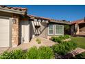 Inviting front entrance with manicured greenery and stone accents around the garage and entry at 11615 N 77Th Dr, Peoria, AZ 85345