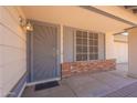 Covered front porch featuring a gray security screen door, red brick accents, and decorative window with a grid pattern at 1165 E Ivanhoe St, Chandler, AZ 85225