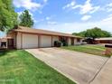 Ranch-style home with a three-car garage, green lawn, and a long driveway at 1306 W 12Th St, Tempe, AZ 85281