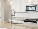 Close up view of a stainless steel microwave, modern faucet, and gas cooktop on a granite countertop at 17334 W Eva St, Waddell, AZ 85355