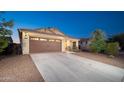 Wide view of a single-story house with a brown garage door and long driveway under a twilight sky at 18344 W Getty Dr, Goodyear, AZ 85338