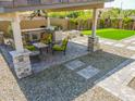 Well-equipped backyard featuring an outdoor kitchen, covered patio, putting green, and mature landscaping at 3915 N Shannon Cir, Mesa, AZ 85215