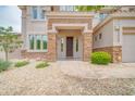 Inviting front entryway with a dark wood door, stone accents, and desert landscaping at 5542 W Big Oak St, Phoenix, AZ 85083