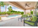 Covered patio area with comfortable seating, ceiling fan, and views of the sparkling pool and lush landscaping at 5542 W Big Oak St, Phoenix, AZ 85083