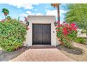 Ornate metal gate flanked by vibrant plants adds curb appeal to this inviting entryway for a private front yard at 6215 E Surrey Ave, Scottsdale, AZ 85254