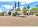 Well-maintained desert landscaping adorns this home's exterior, featuring stucco walls, and palm trees for added privacy at 6215 E Surrey Ave, Scottsdale, AZ 85254
