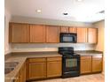 A kitchen with matching wooden cabinets, black appliances, neutral countertops, and recessed lighting at 6388 W Ruth Ave, Glendale, AZ 85302
