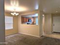A living room area that shows a large window, carpet flooring, neutral walls, and an open view to the kitchen at 6388 W Ruth Ave, Glendale, AZ 85302
