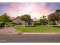 Charming home with a well-manicured lawn, decorative bushes, and flowering trees at 7722 W Michigan Ave, Glendale, AZ 85308