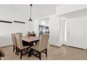 Bright dining area with a wooden table, upholstered chairs, neutral tile floor, and view into the kitchen at 9322 E Jenan Dr, Scottsdale, AZ 85260