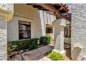 Stucco exterior of a home with a wooden pergola, small decorative bushes and desert landscaping at 9322 E Jenan Dr, Scottsdale, AZ 85260